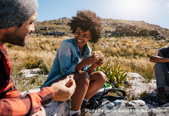 A smiling black woman takes a break with her fellow hikers